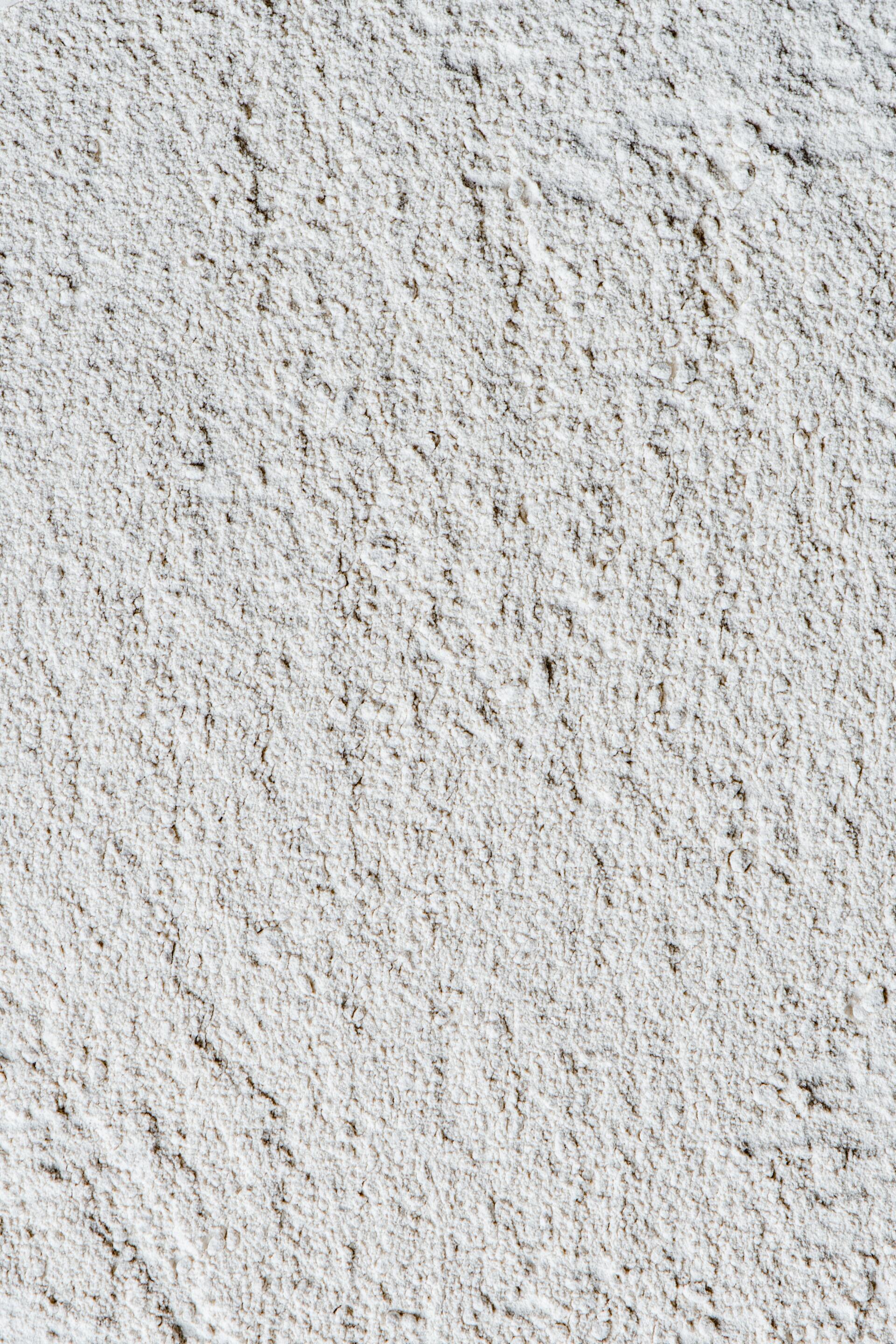 Close-up of a light gray, rough stucco or concrete wall texture
