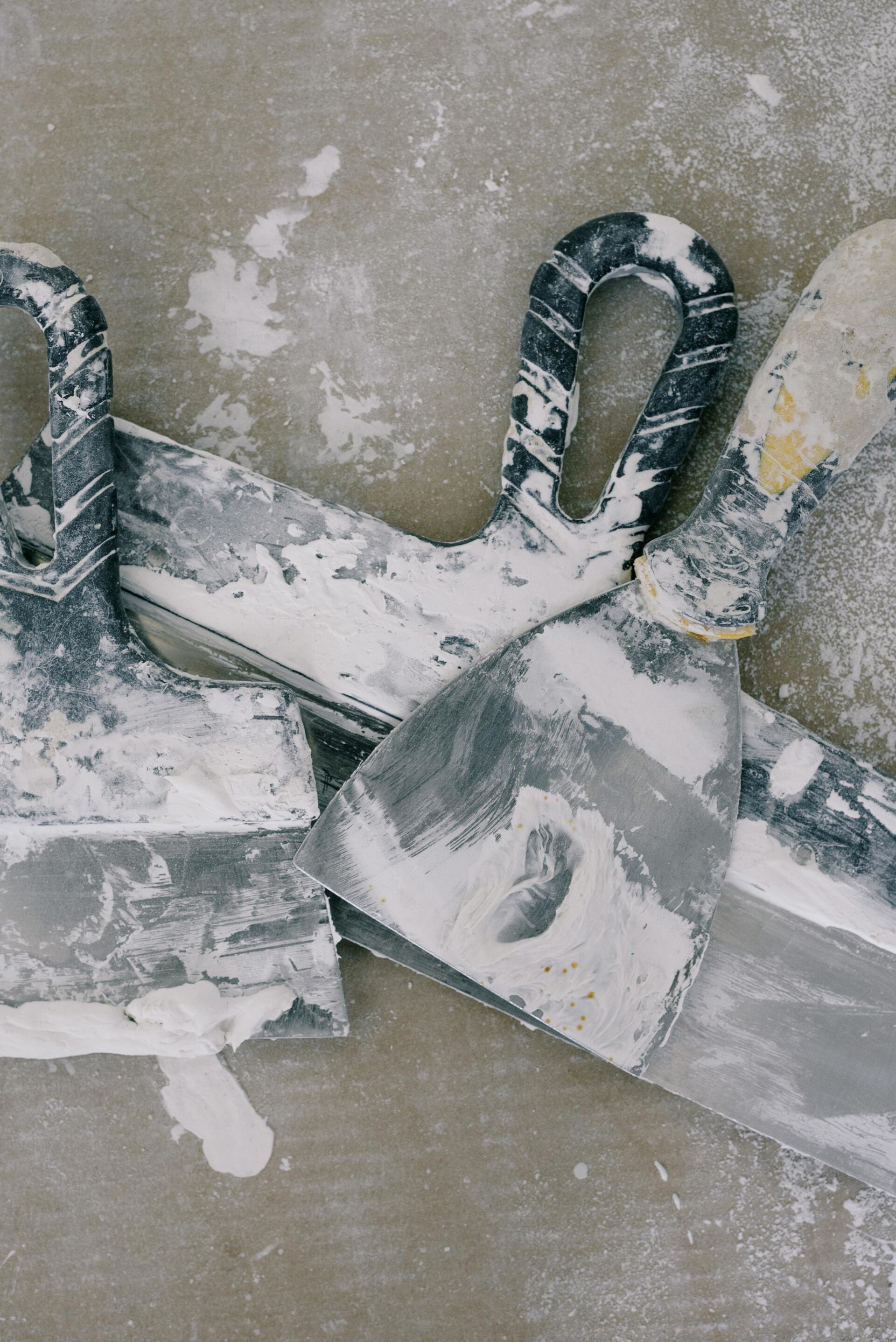 Dusty metal tools and loops coated in white powder on a concrete floor.