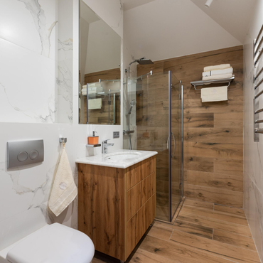 Modern bathroom with glass shower, wood vanity, and marble accents